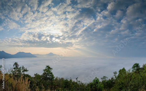 Scenic mountain view misty morning of the hill and mountain around with sea of mist above Mekong river and green forest with cloudy sky background, sunrise at Phu Thok View Point, Chiang Khan, Loei.