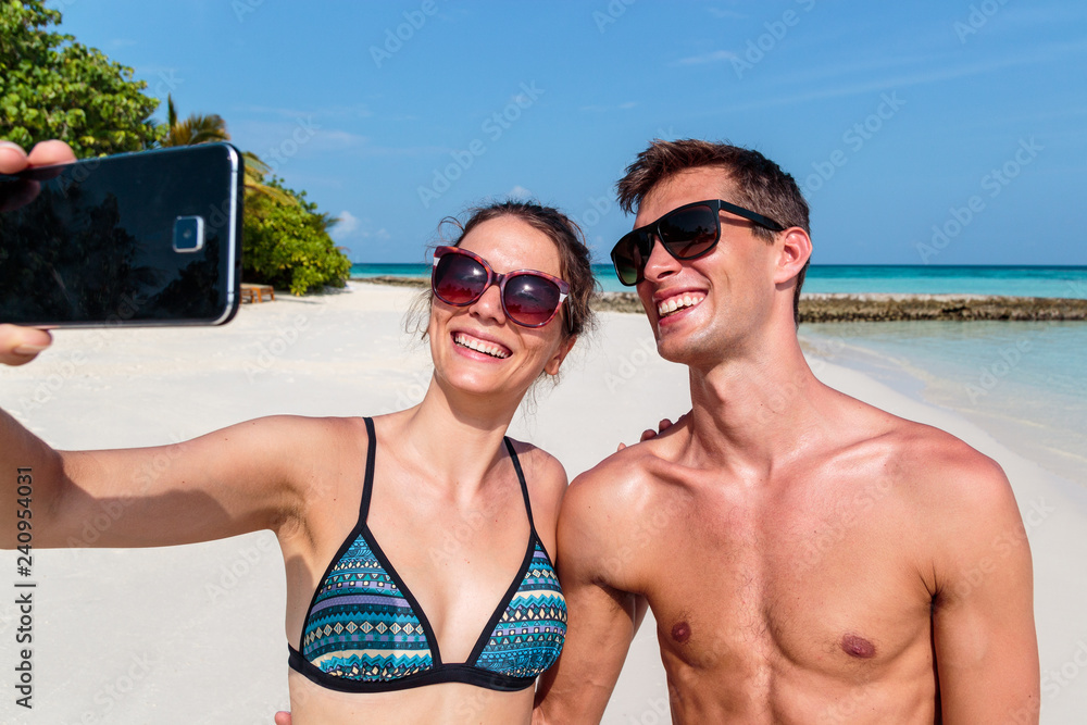 Happy young couple taking a selfie. Tropical island as background Happy young couple taking a selfie. Tropical island as background