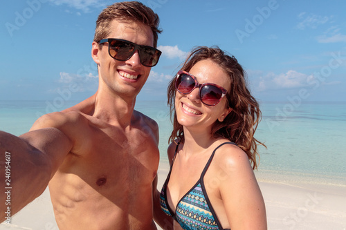 happy young couple taking a selfie, clear blue water as background. hug