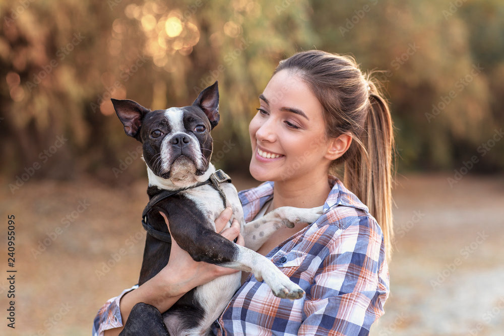 Young girl holding on hands her boston terrier black and white dog on the beach Young girl holding on hands her boston terrier black and white dog on the beach