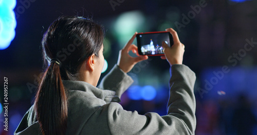 Woman take photo on smart phone in the street at night