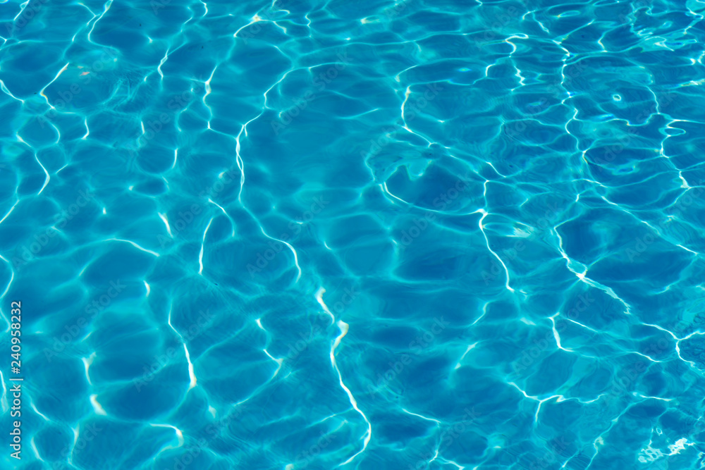 Blue water in swimming pool background. Ripple Water in swimming pool with sun reflection. Blue swimming pool rippled water detail.