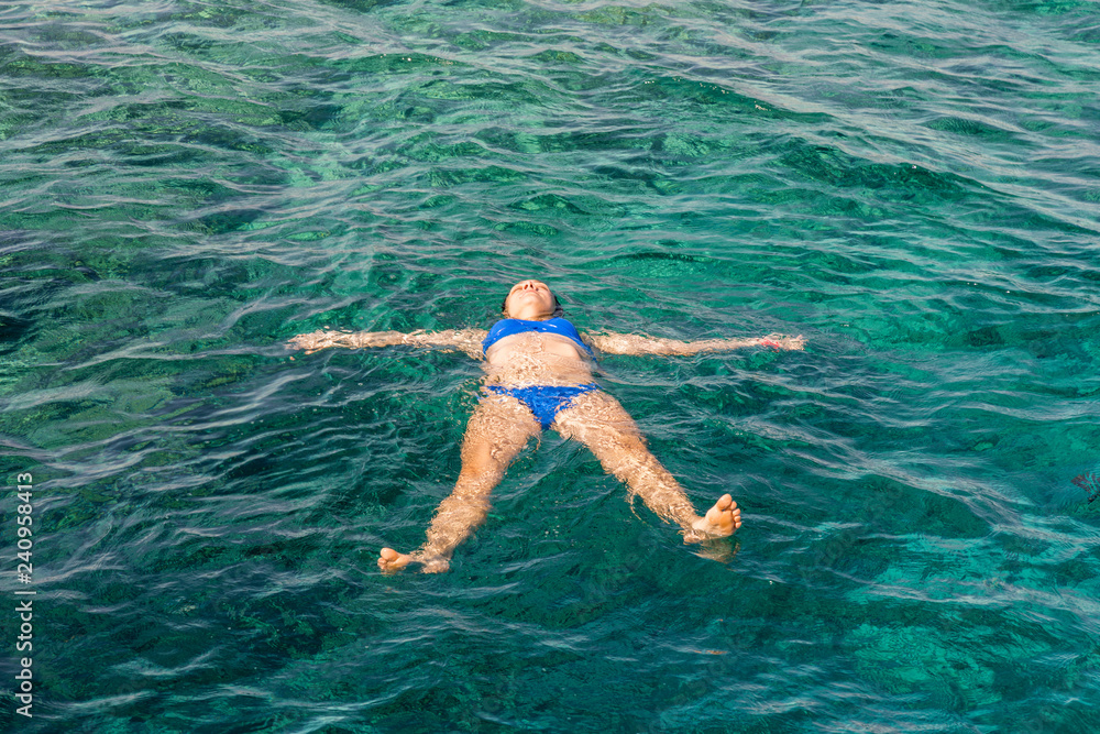 Young woman in bikini swimming in clear water. Woman swimmer swimming in blue sea. Woman swiming in the sea.