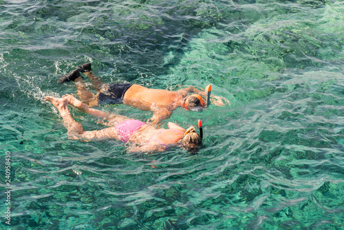 Married couple snorkeling in tropical water on vacation. Woman swimming in blue sea. Snorkeling girl in full-face snorkeling mask. People in flippers and masks in the clear sea.