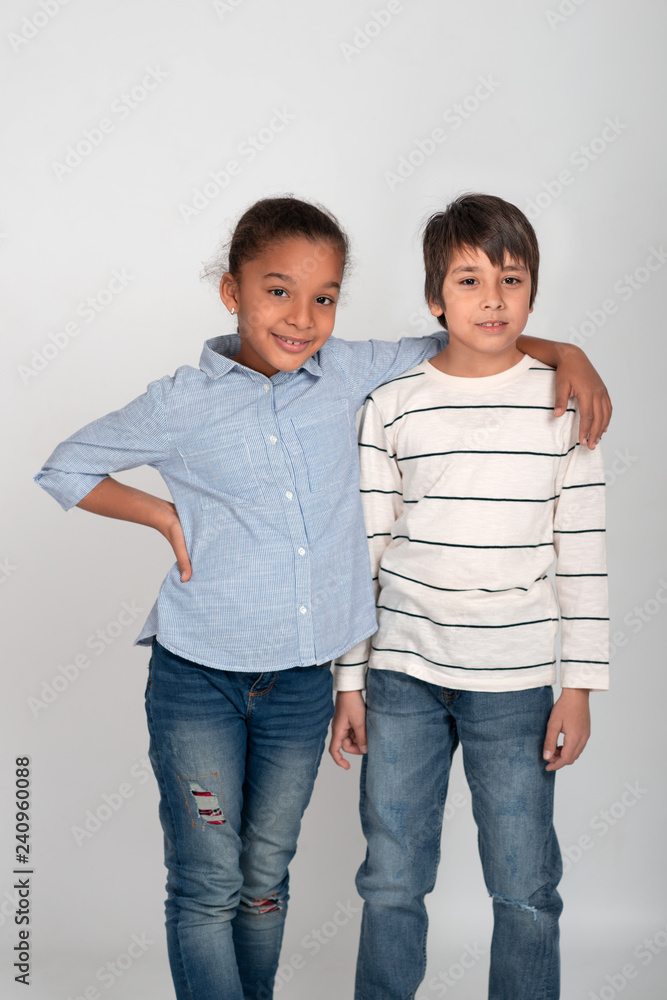 Studio shot of two friends, boy and girl, wearing jeans and shirts. Girl  smiling with his hand on the boy's shoulder. Stock Photo | Adobe Stock