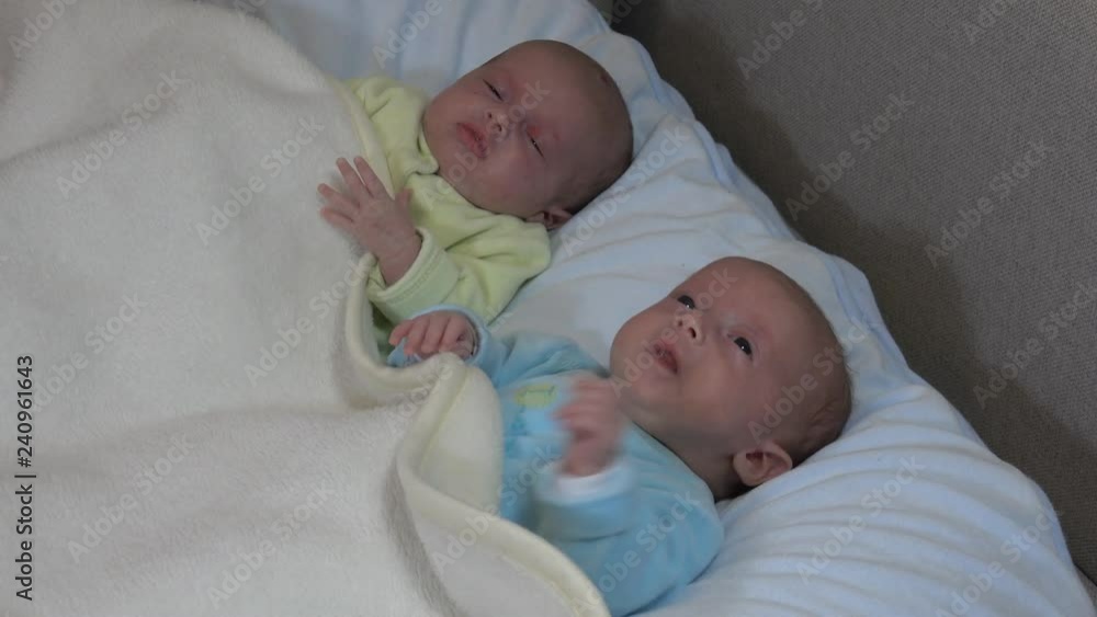 Two girls sisters lie on the bed. Two baby twins on the bed, crying. Two girls sisters lie on the bed. Two baby twins on the bed, crying.