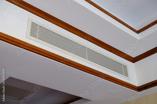 Perspective view of air conditioner embedded on building ceiling at the corner of a room