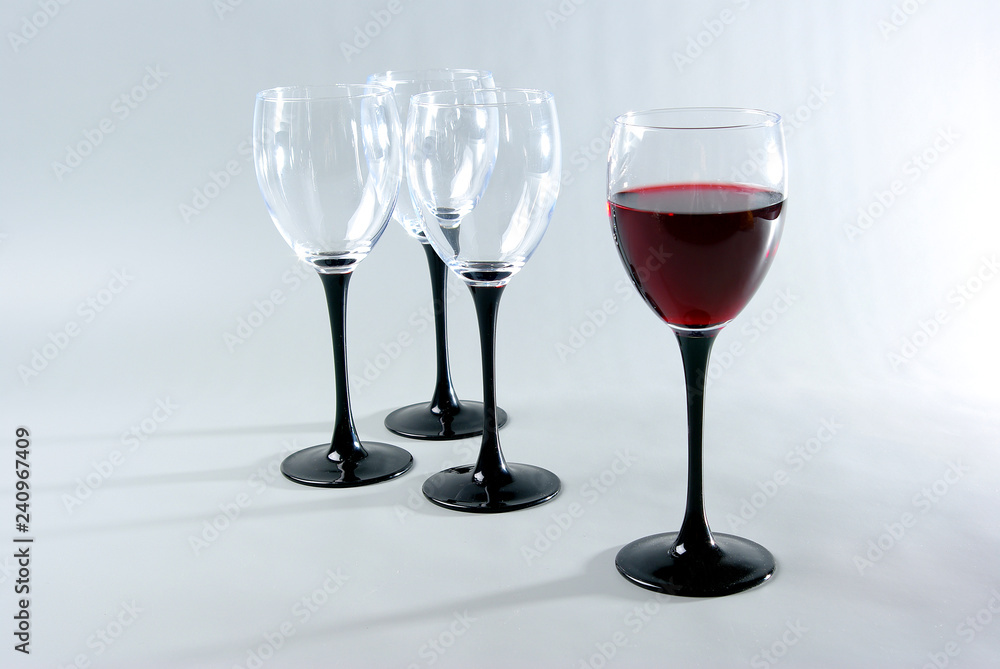 Fototapeta premium One glass of red wine and three empty glasses