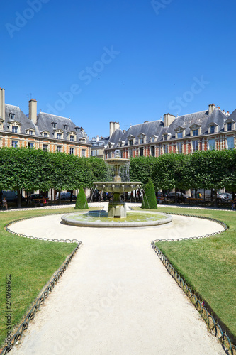 Place des Vosges, path with fountain in the garden in Paris in a sunny summer day, clear blue sky