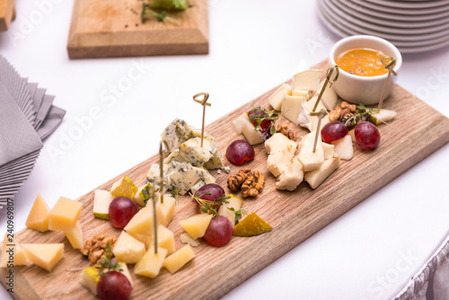 pieces of different types of cheese with grape nuts and sauce on a wooden Board, cheese plate
