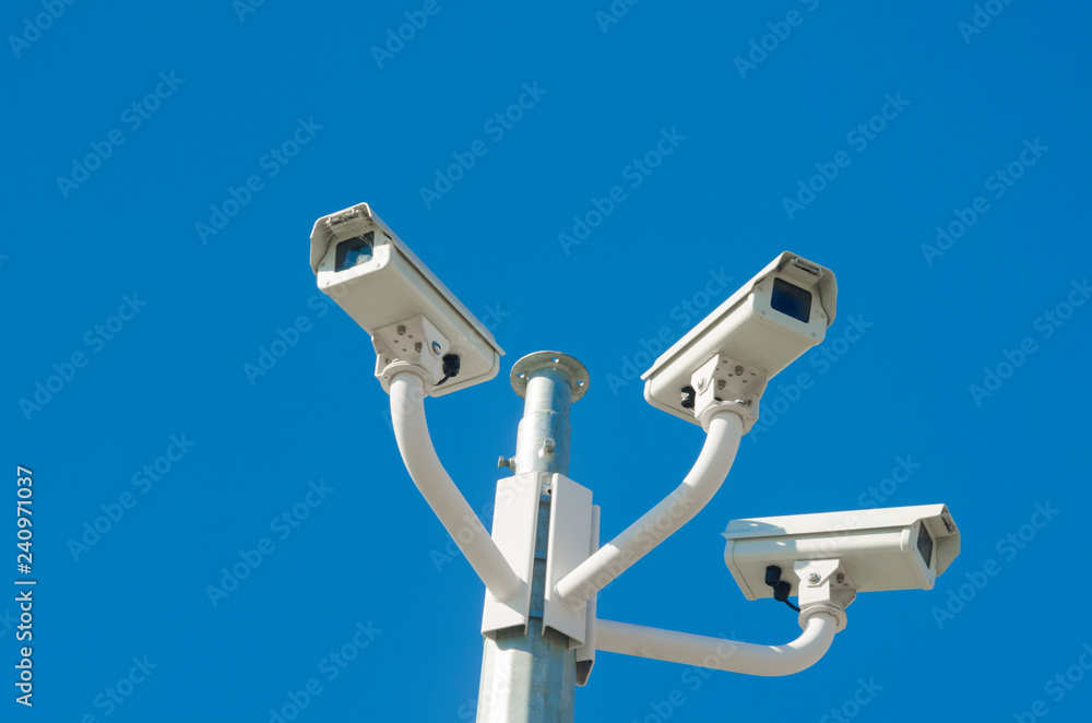 Three CCTV cameras against blue sky