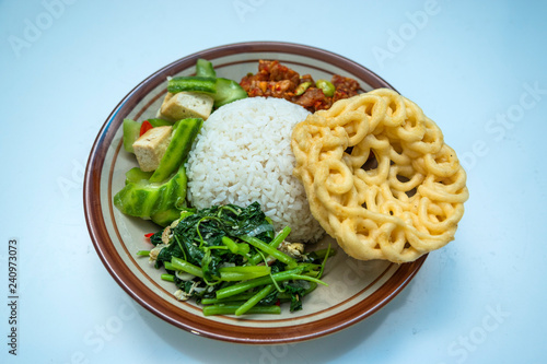 Indonesian home made style food nasi campur or mixed rice with krupuk, tempe balado, pete, sayur bayam, tahu dan sayur oyong