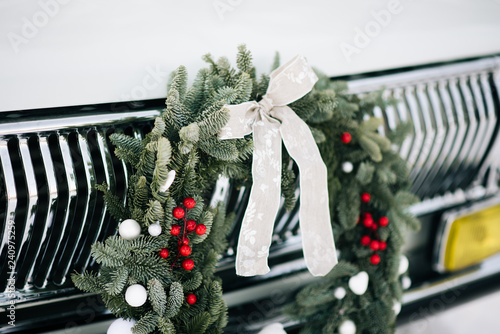 Classic christmas wreath on  retro car. Holiday car wreath. Retro car decorated with christmas wreath for holidays.