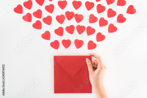 partial view of woman holding envelop under dozen red heart symbols isolated on white, st valentine day concept