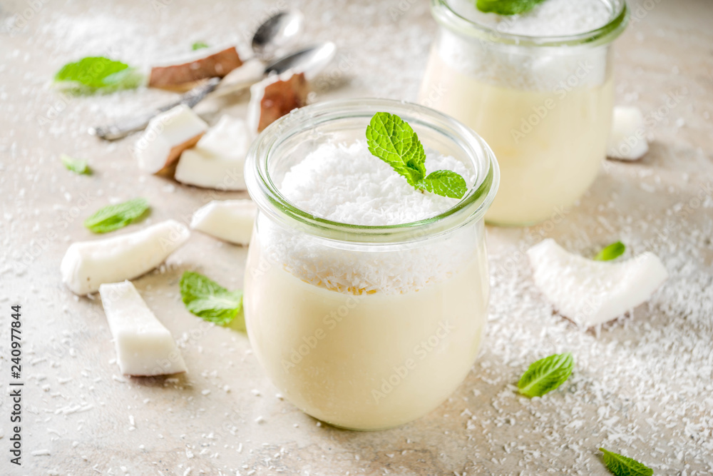 Vegan sweet food, coconut panna cotta dessert in glass jar with coconut chips and mint leaves, light concrete stone background copy space Vegan sweet food, coconut panna cotta dessert in glass jar with coconut chips and mint leaves, light concrete stone background copy space