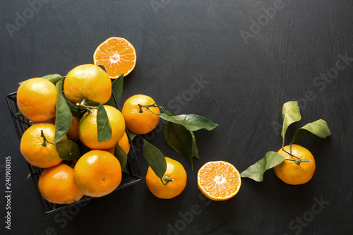 Fresh mandarins with leaves on black. Healthy eating concept. Copy space.