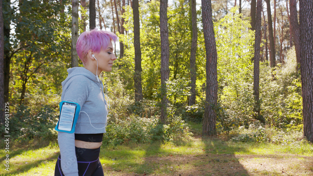 A young y with pink hair jogging in the forest. Medium shot A young y with pink hair jogging in the forest. Medium shot