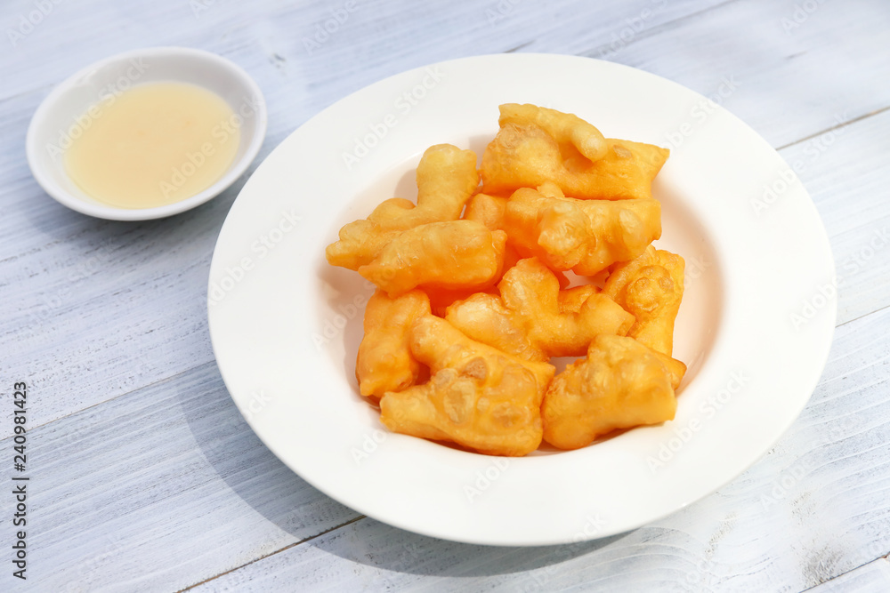Deep-fried dough stick with sweetened condensed milk on wooden background. Deep-fried dough stick with sweetened condensed milk on wooden background.