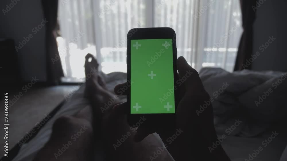 Close up Young Man laying on the bed holding smartphone green screen