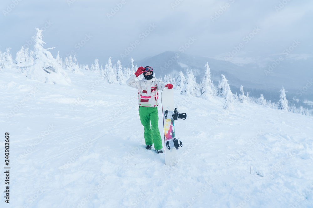 at the top of the mountain winter mountain snowboard. woman holding snowboard.