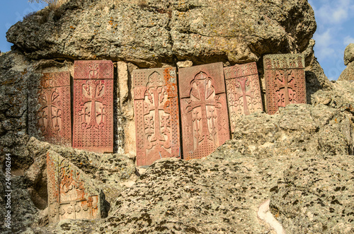 Group of medieval khachkars installed on the wall of the cave Church in the mountains of Geghama ridge,on the territory of Geghard monastery in Armenia photo