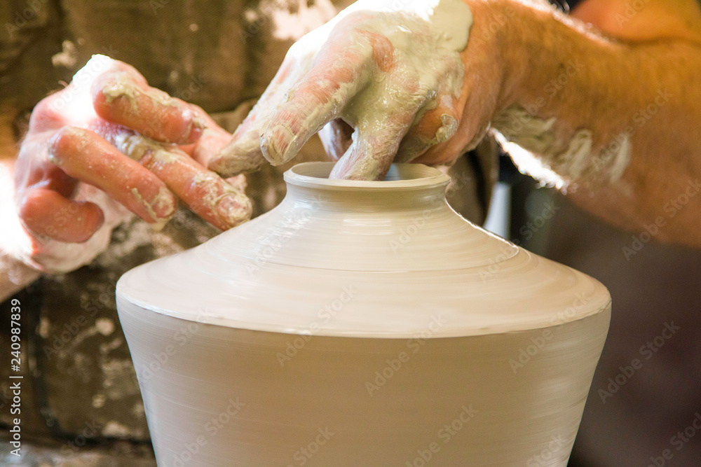 Artist potter in the workshop sculpting ceramic vase. Hands closeup. Small artistic craftsmen business concept. 