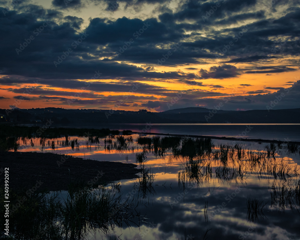 Sunset over lake in Italy with reflections of clouds in water