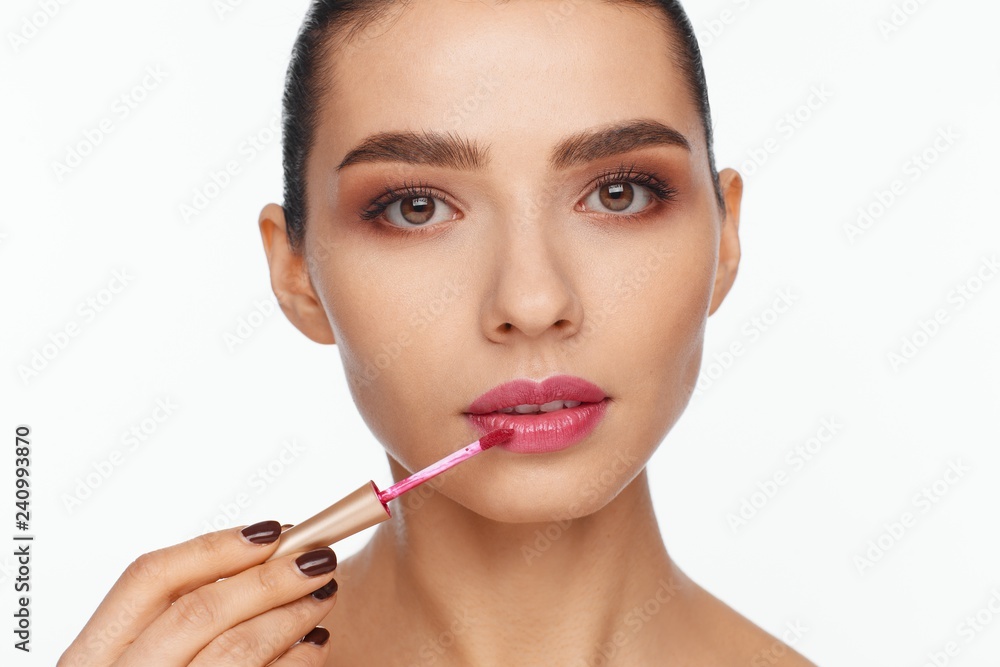 Portrait of a beautiful young woman putting lipstick on her lips Portrait of a beautiful young woman putting lipstick on her lips