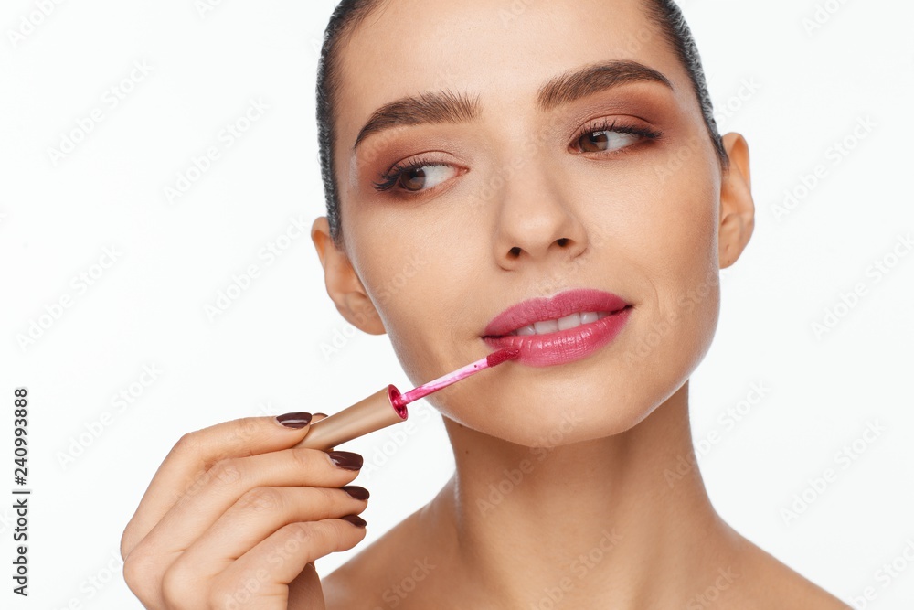 Portrait of a beautiful young woman putting lipstick on her lips Portrait of a beautiful young woman putting lipstick on her lips