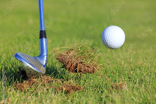 chipping a golf ball out of the rough grass with a big divot