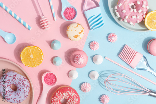 Kitchen utensils and tools, pastries and sweets on a pink and blue background. Top view. Copy space.
