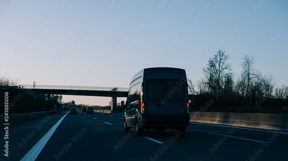 Van silhouette driving at dusk on European highway German autobahn to deliver on time the merchandise cargo delivery and shipping concept 