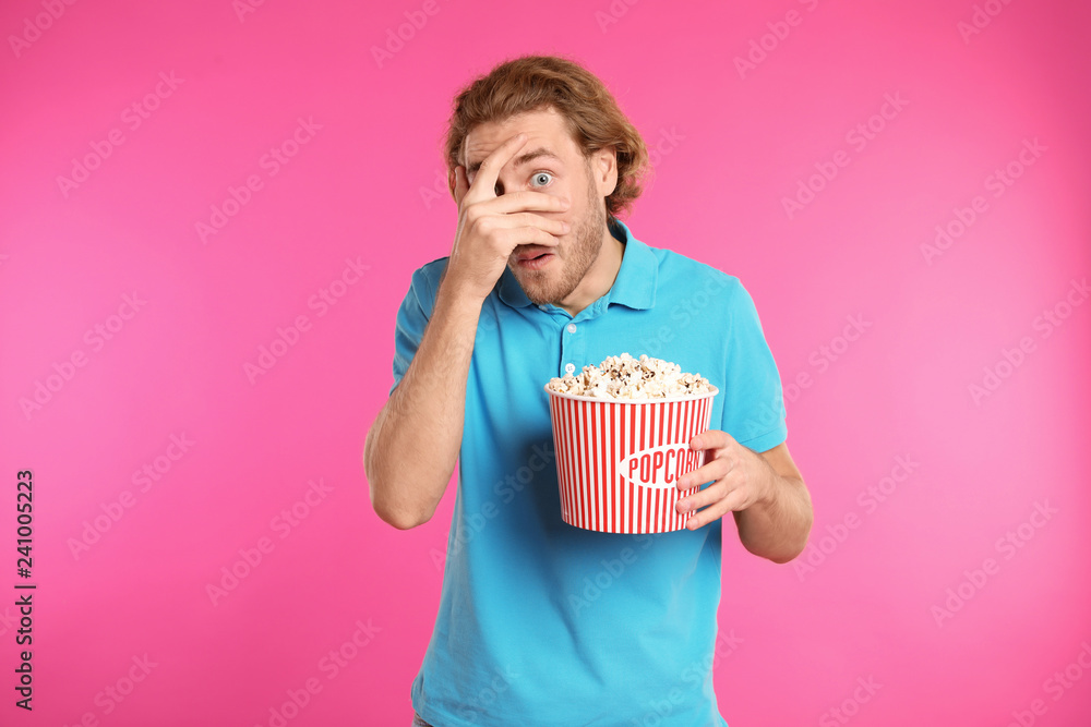 Fototapeta premium Emotional man with popcorn during cinema show on color background