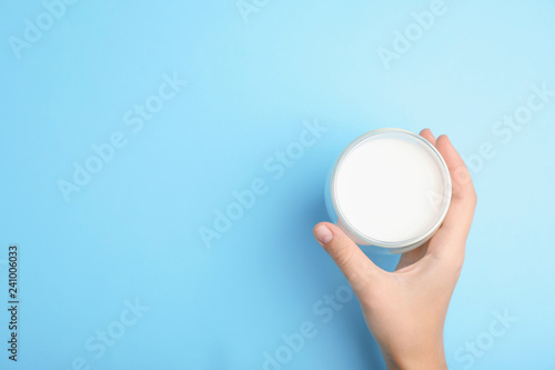 Woman holding glass of milk on color background, top view. Space for text