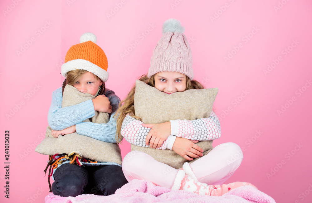 Siblings wear winter warm hats sit on pink background. Children boy and girl warm up with pillows and hats. Stay warm and comfortable. Warm up your winter wear with cute and cozy accessories Siblings wear winter warm hats sit on pink background. Children boy and girl warm up with pillows and hats. Stay warm and comfortable. Warm up your winter wear with cute and cozy accessories