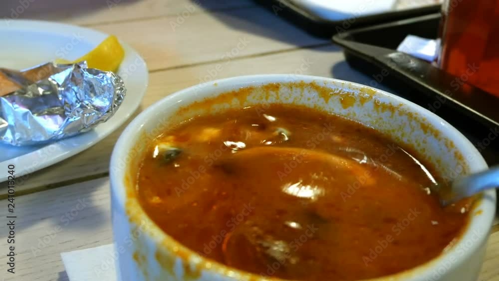 Soup from meat of vegetables and tomatoes - solyanka. With the addition of olives and a slice of lemon. Stir in a metal spoon. Close-up. Soup from meat of vegetables and tomatoes - solyanka. With the addition of olives and a slice of lemon. Stir in a metal spoon. Close-up.