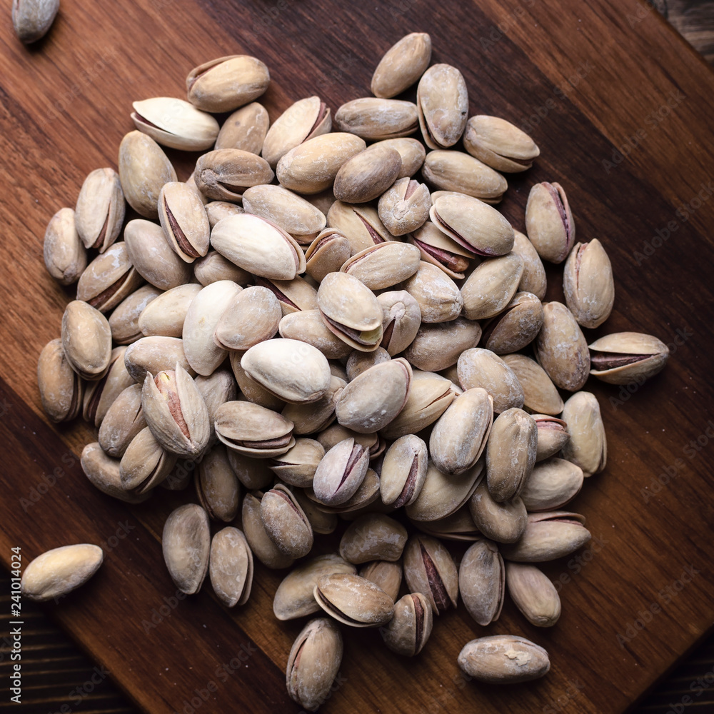 Delicious salted pistachios on wooden background Delicious salted pistachios on wooden background