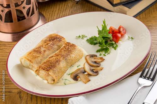 Crepes stuffed with sour cream and mushroom for breakfast on wooden table