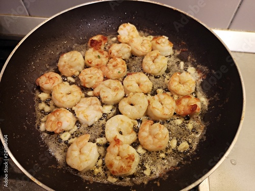 Cooking shrimps with butter in a black pan