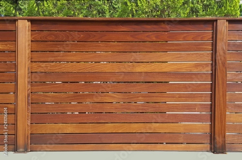 The fence around the house of wooden planks and wooden pillars, based on a concrete base