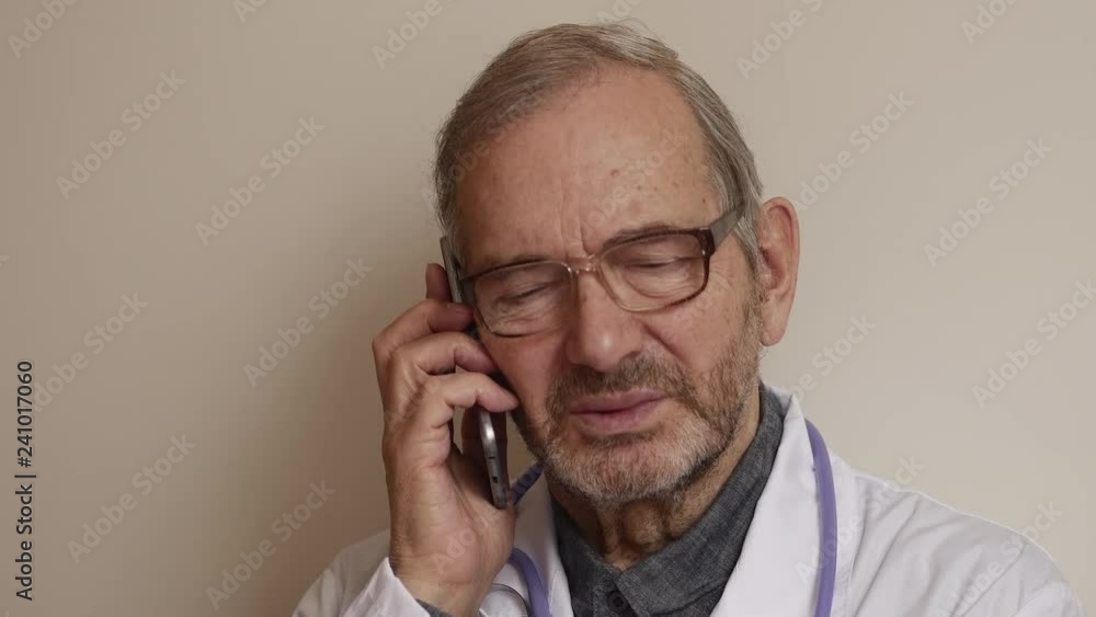 Elderly Doctor With Glasses Talking On Mobile Phone Elderly Doctor With Glasses Talking On Mobile Phone