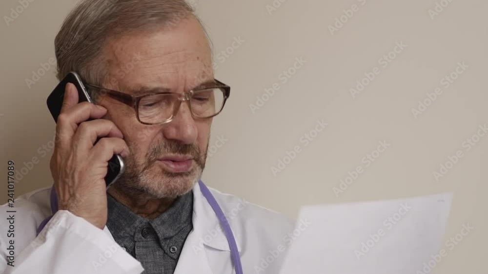 Elderly Doctor With Glasses Talking On Mobile Phone Elderly Doctor With Glasses Talking On Mobile Phone