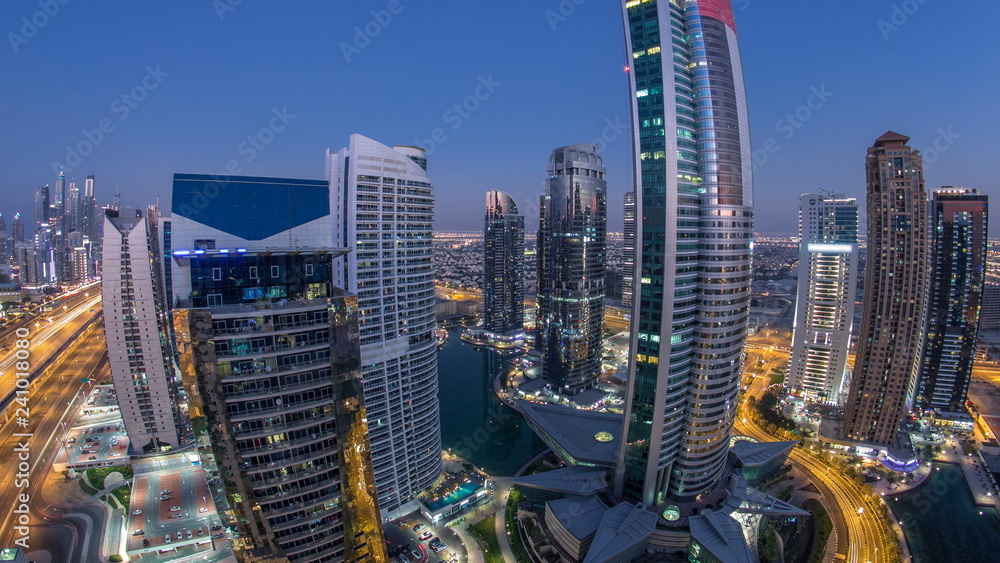 Buildings of Jumeirah Lakes Towers after sunset with traffic on the road day to night timelapse.