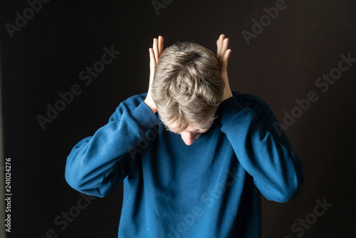 young stressed male protecting his ears from loud irritative noises f