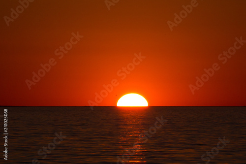 Half red hot African sun setting behind the horizon and a rippled Lake Kariba, Zimbabwe (ID: 241025068)