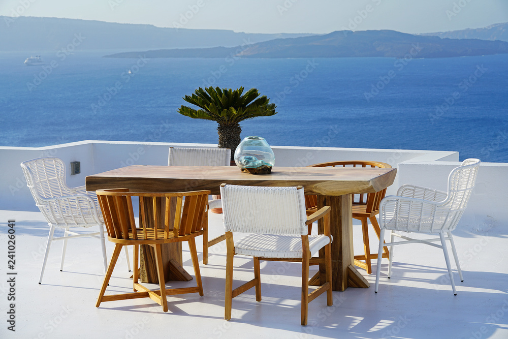 Beautiful location with wooden table and chairs overlooking the Caldera in Santorini