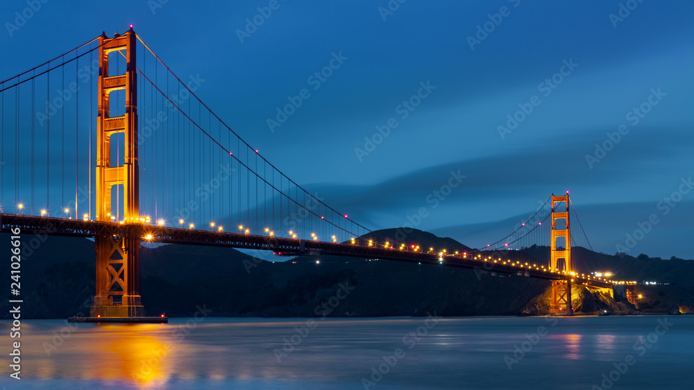Nighttime view of Golden Gate Bridge on a dark blue sky background; California