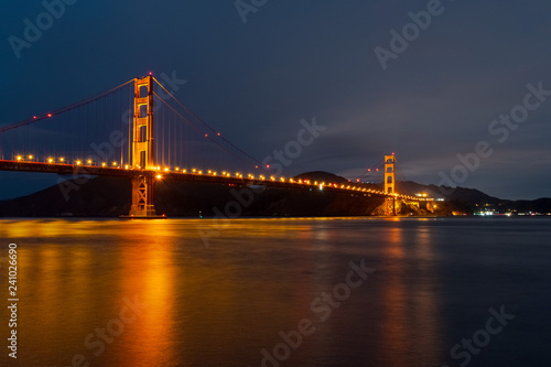 Nighttime view of Golden Gate Bridge reflected in the blurred water surface of San Francisco bay  California