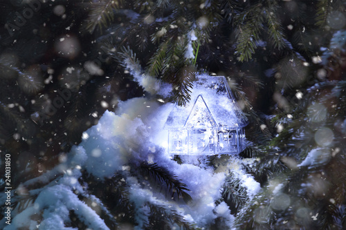 Decorative house, Christmas decoration and a garland on a branch of a Christmas tree. Winter, snow, Christmas or New Year. Abstract background, soft focus