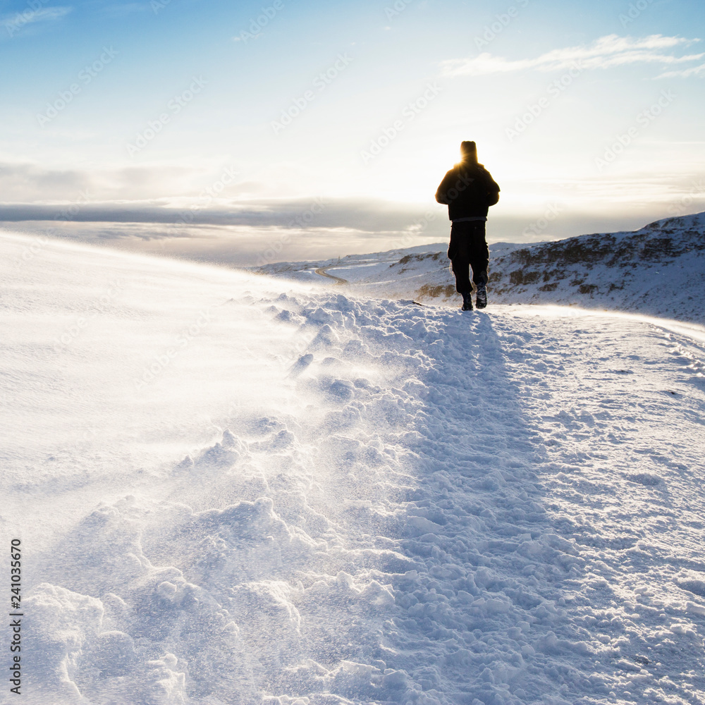 Walker in Reykjadalur steam valley near Reykjavik, in Iceland with hills covered in white during winter